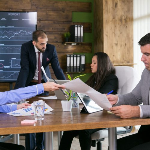 Middle age business woman giving charts to her young colleague in the conference room.